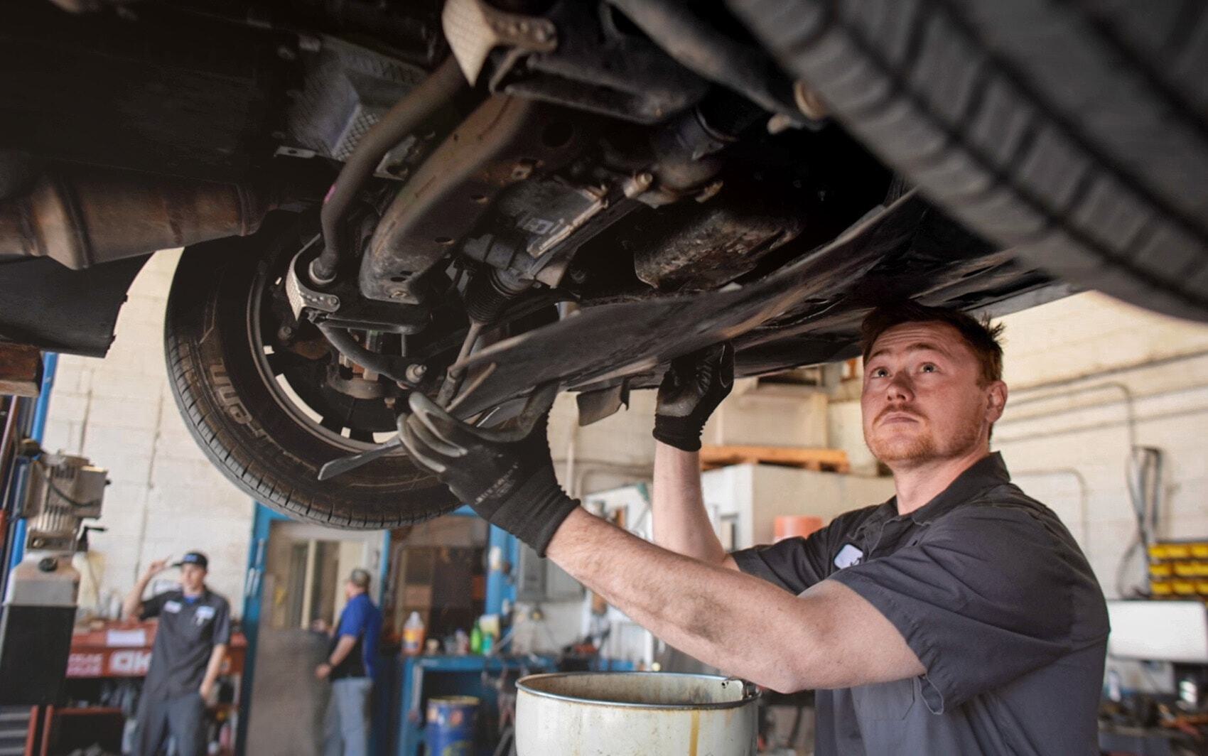Power steering technician inspecting underneath vehicle