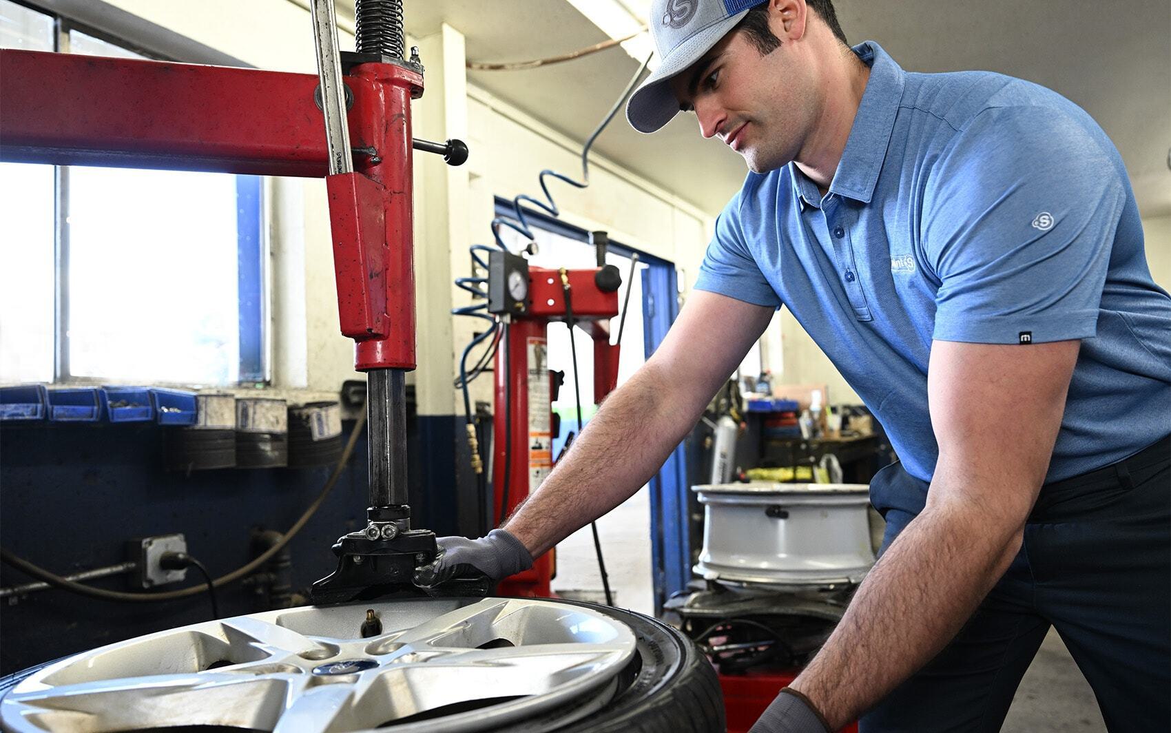 Tire install technician using tire machine on wheel