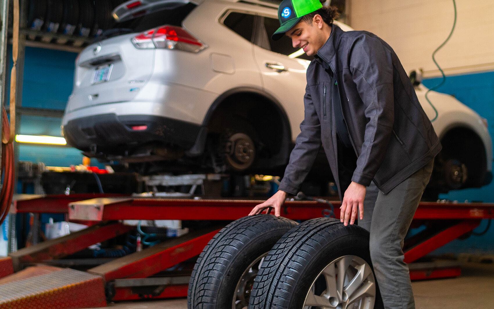 Tire install worker moving tires near car on lift