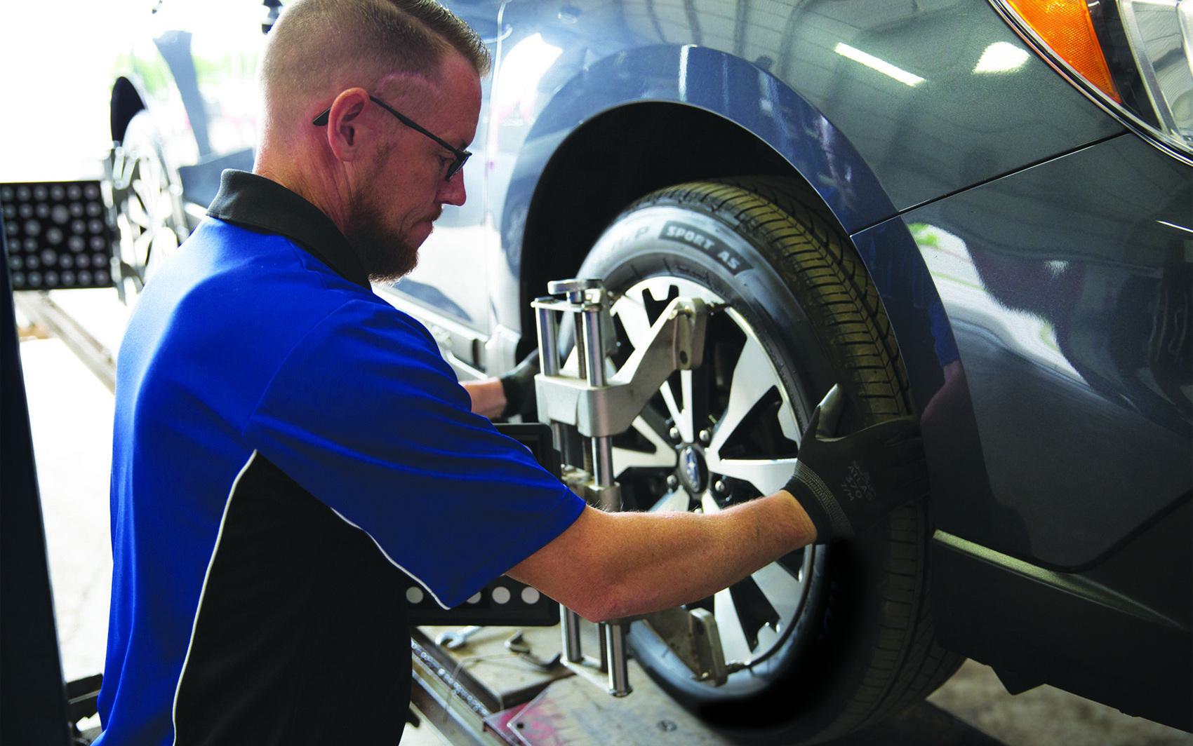 Wheel alignment technician adjusting alignment equipment on wheel